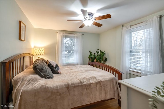 bedroom featuring a ceiling fan, dark wood-type flooring, and multiple windows