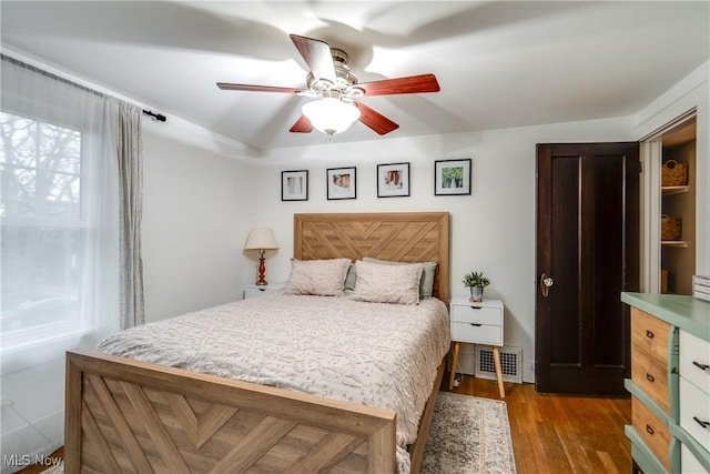 bedroom featuring ceiling fan, visible vents, and wood finished floors