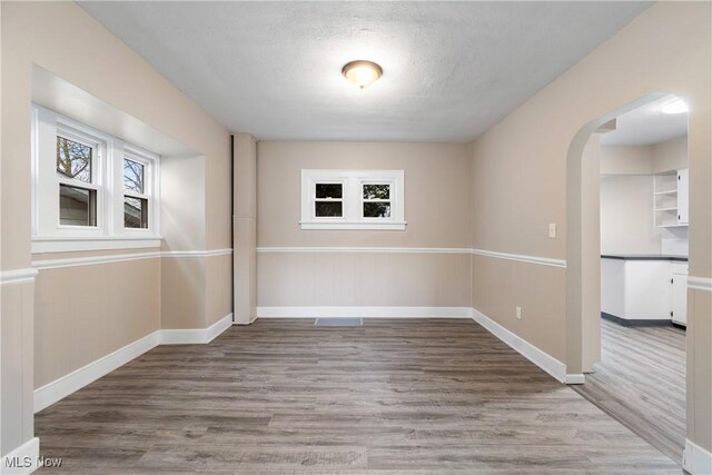 1862 17th St SW, Akron, OH 44314 - spare room featuring baseboards, wood finished floors, arched walkways, and a textured ceiling