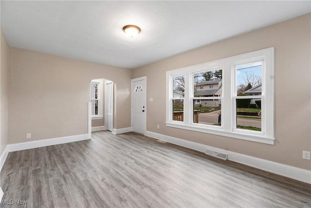 1862 17th St SW, Akron, OH 44314 - empty room with wood finished floors, arched walkways, baseboards, and visible vents