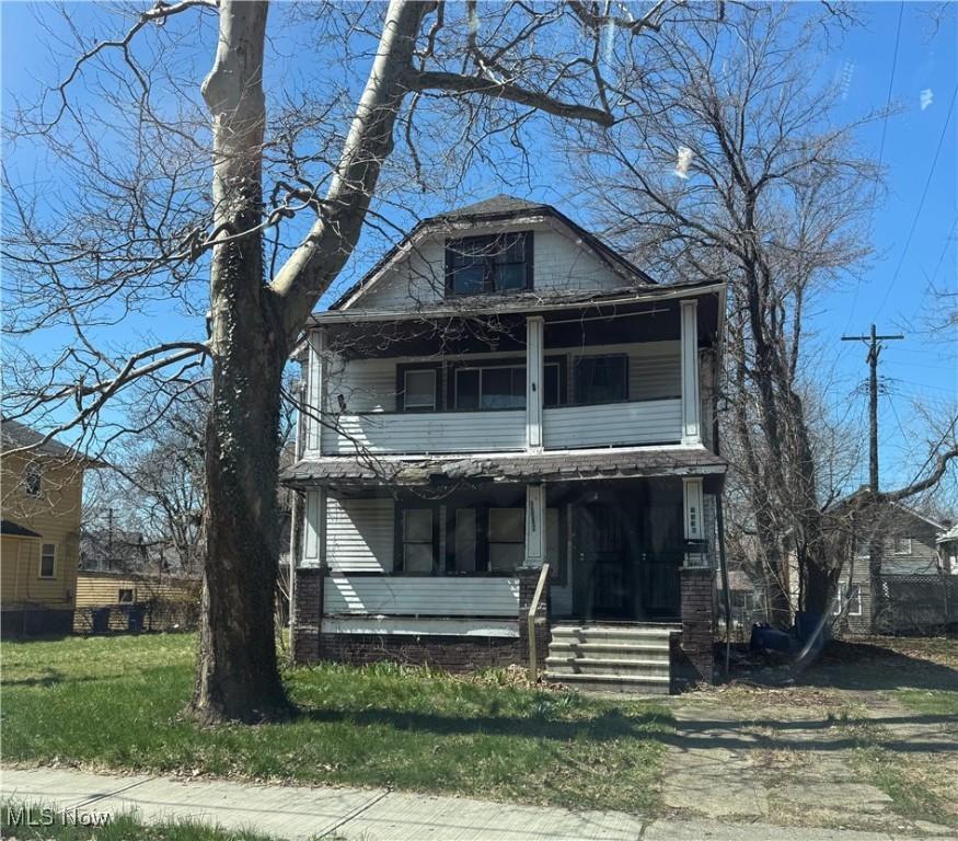 1136 E 145th St, Cleveland, OH 44110 - traditional style home featuring covered porch, a balcony, and a front lawn