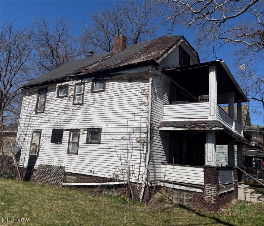 1136 E 145th St, Cleveland, OH 44110 - view of home's exterior with a balcony, a lawn, and a chimney
