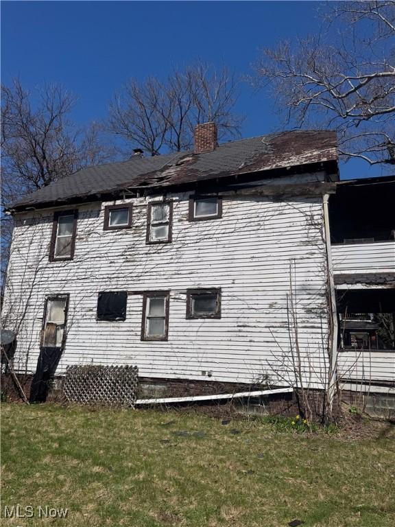 1136 E 145th St, Cleveland, OH 44110 - back of property with a lawn and a chimney