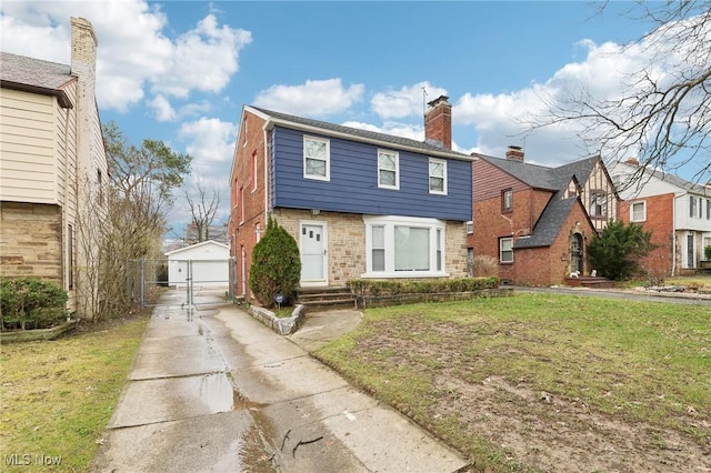 colonial inspired home featuring an outdoor structure, brick siding, driveway, and a chimney