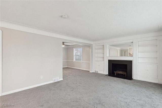 unfurnished living room featuring a fireplace with flush hearth, baseboards, built in features, and carpet flooring