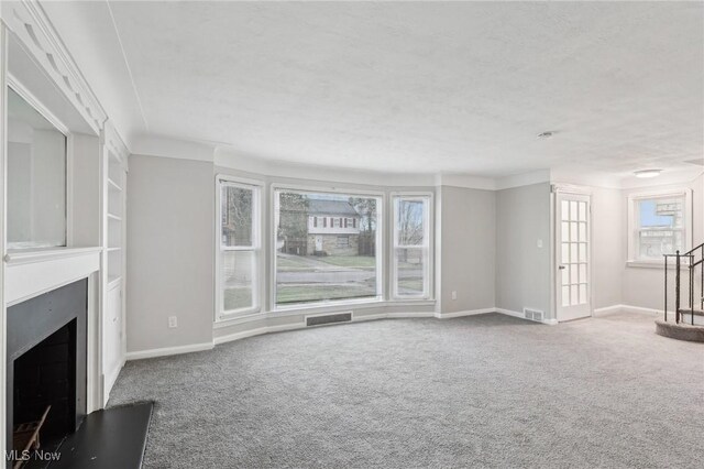 unfurnished living room featuring a wealth of natural light, a fireplace, visible vents, and carpet
