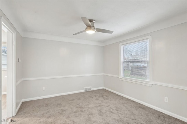 carpeted spare room featuring baseboards, ceiling fan, and visible vents