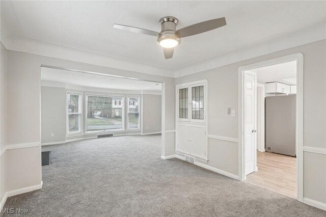 spare room with baseboards, visible vents, carpet floors, and a ceiling fan