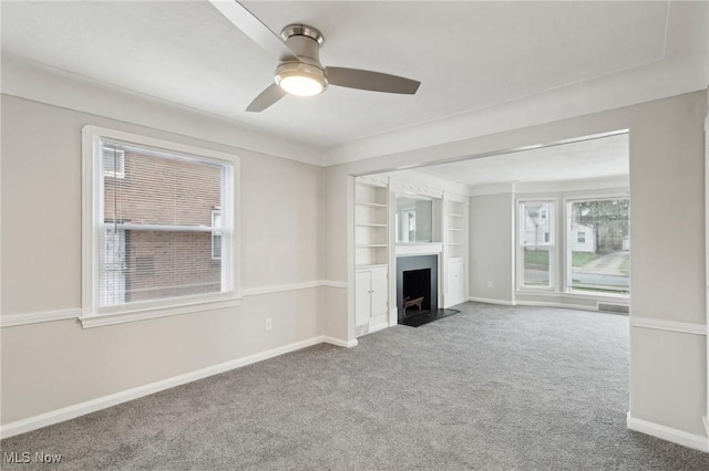 unfurnished living room featuring baseboards, carpet flooring, and built in shelves