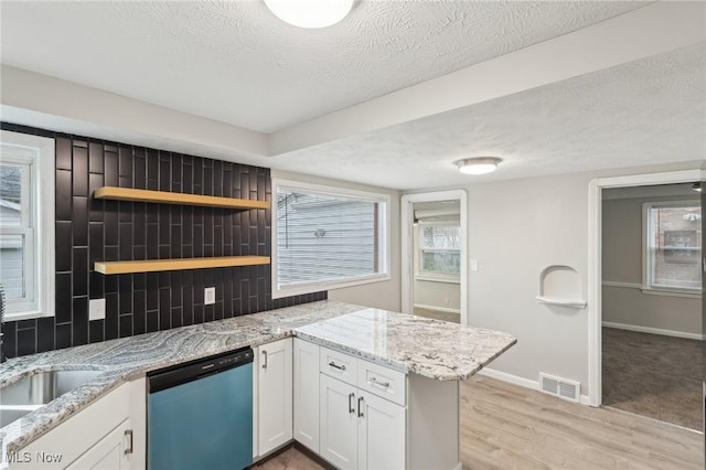 kitchen featuring a textured ceiling, white cabinets, visible vents, dishwasher, and backsplash