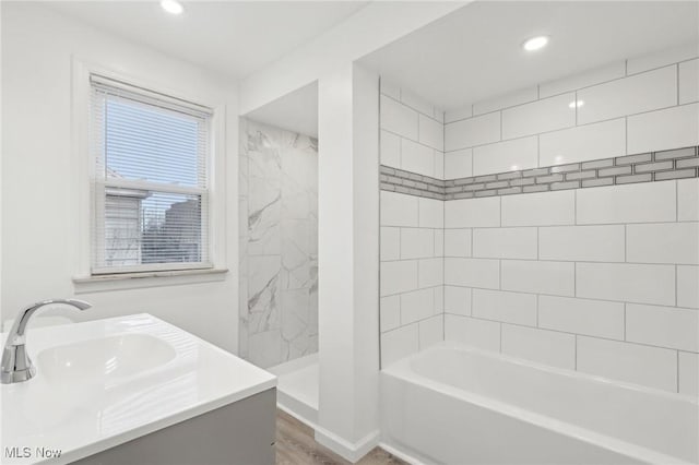 bathroom with recessed lighting, a bathing tub, a sink, and walk in shower