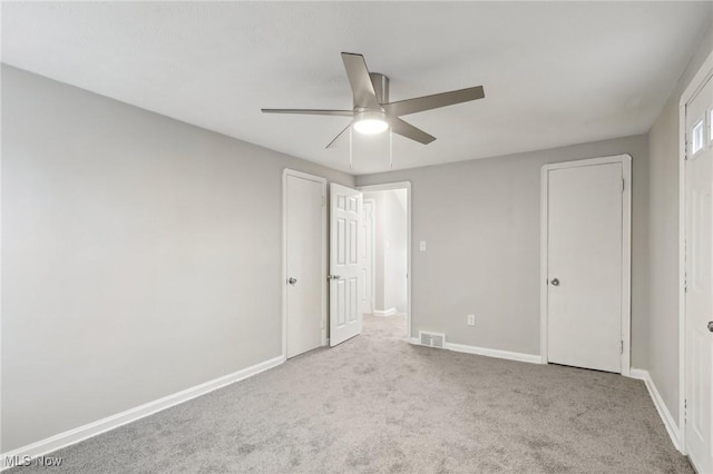 unfurnished bedroom with baseboards, carpet floors, ceiling fan, and visible vents
