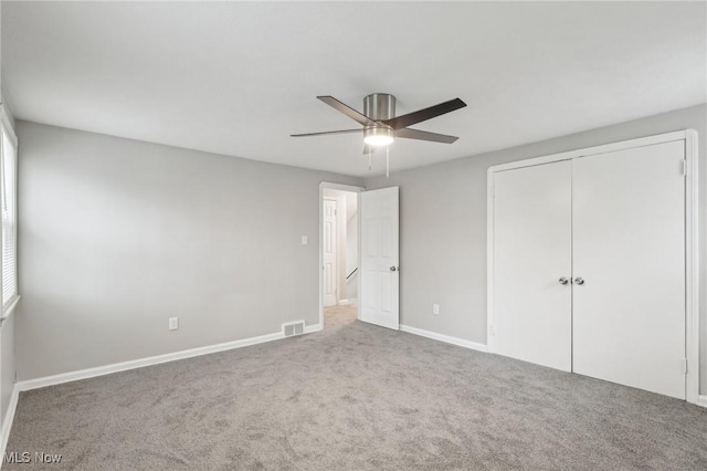 unfurnished bedroom featuring a closet, carpet flooring, visible vents, baseboards, and a ceiling fan