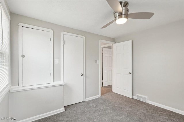 unfurnished bedroom featuring carpet, baseboards, ceiling fan, and visible vents