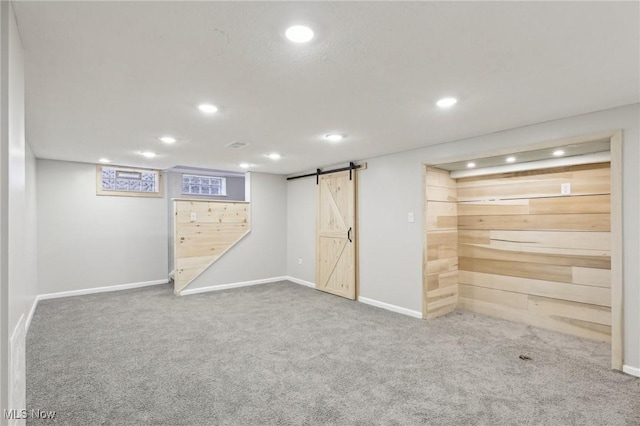 finished basement featuring recessed lighting, a barn door, baseboards, and carpet flooring