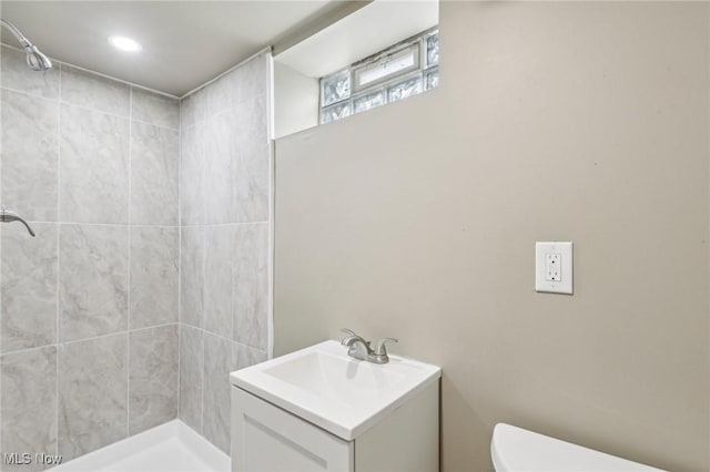 bathroom featuring toilet, vanity, and tiled shower