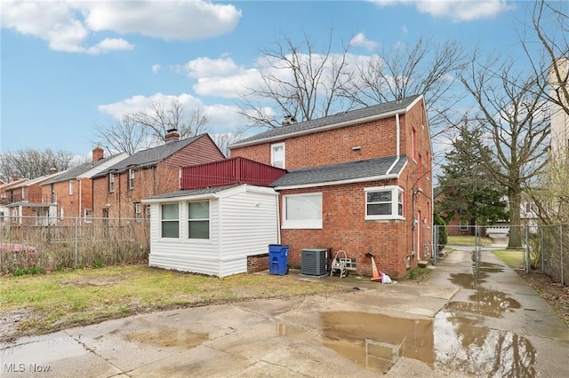 rear view of property with concrete driveway, fence, a gate, brick siding, and a shingled roof