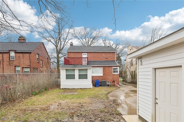 back of house with brick siding, a fenced backyard, a balcony, central AC unit, and a lawn
