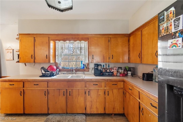 kitchen featuring light countertops, a sink, stainless steel refrigerator with ice dispenser, and brown cabinets