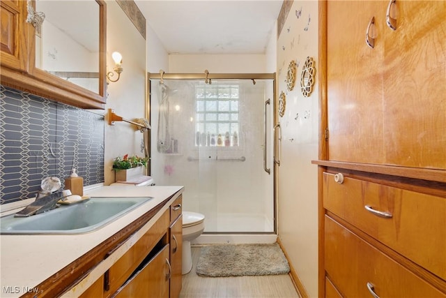 full bath with toilet, vanity, tasteful backsplash, and a stall shower