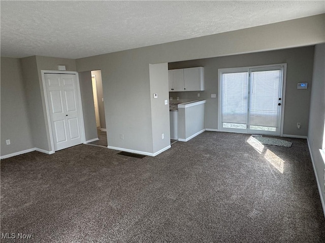 4225 E 93rd St, Cleveland, OH 44105 - unfurnished living room featuring a textured ceiling, baseboards, and dark carpet