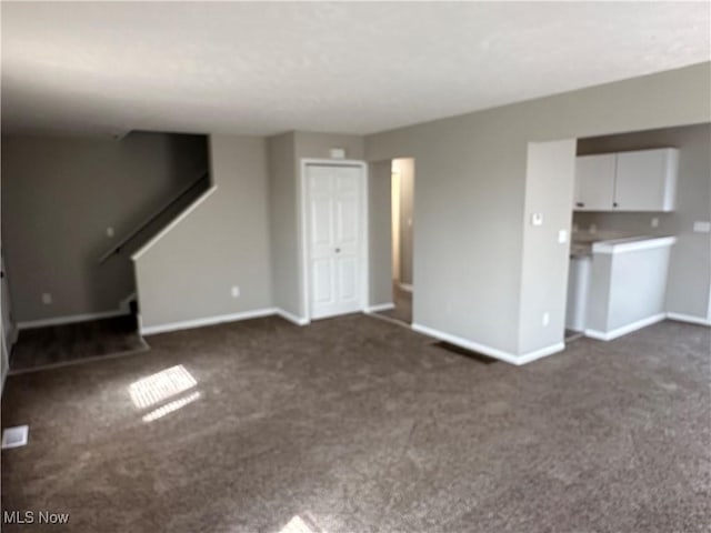 4225 E 93rd St, Cleveland, OH 44105 - unfurnished living room with dark carpet, baseboards, and stairway