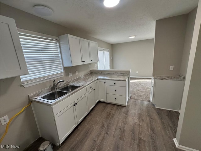 4225 E 93rd St, Cleveland, OH 44105 - kitchen featuring a sink, a peninsula, dark wood-style flooring, white cabinetry, and light countertops