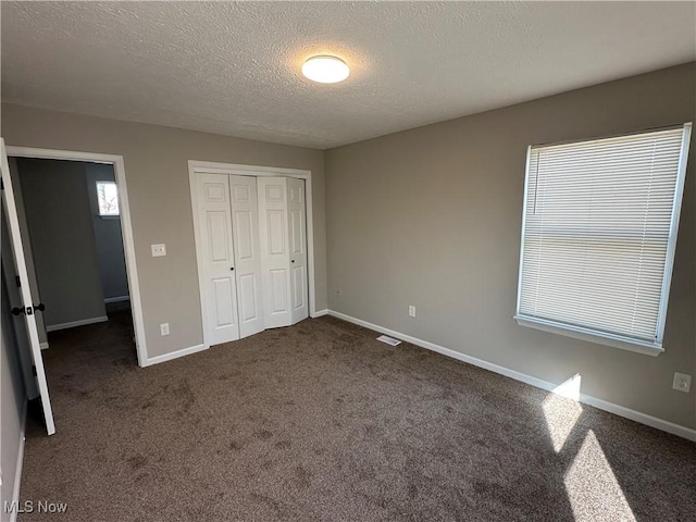 4225 E 93rd St, Cleveland, OH 44105 - unfurnished bedroom with a textured ceiling, a closet, dark colored carpet, and baseboards