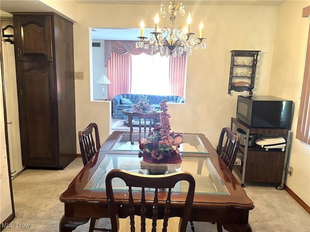 dining area featuring visible vents, light colored carpet, a notable chandelier, and baseboards