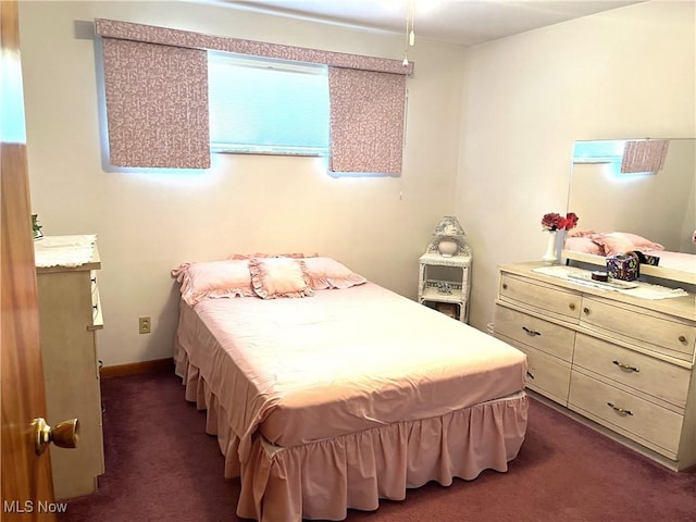 bedroom featuring dark carpet and baseboards