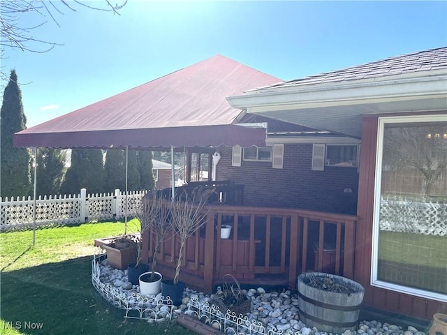 wooden terrace featuring fence and a lawn