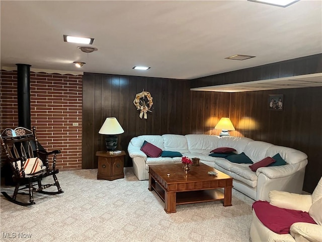 living area featuring light carpet, wood walls, and a wood stove