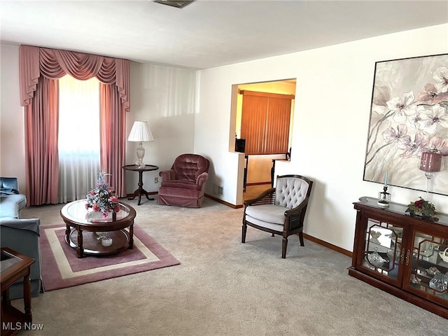carpeted living area featuring baseboards