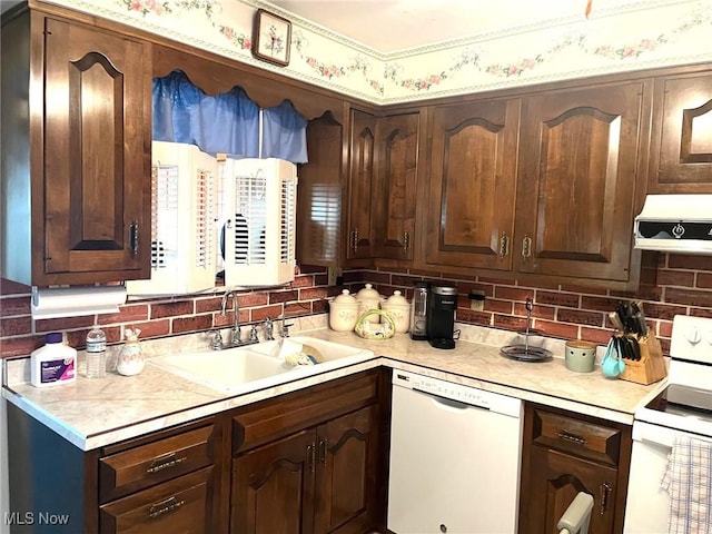 kitchen with white appliances, under cabinet range hood, light countertops, a sink, and decorative backsplash
