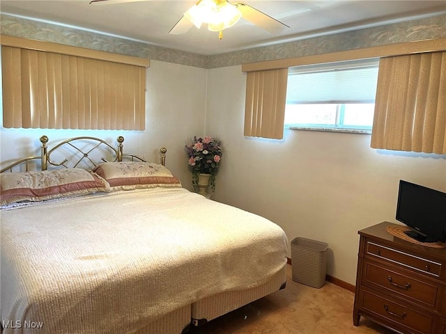 bedroom featuring baseboards, light colored carpet, and a ceiling fan
