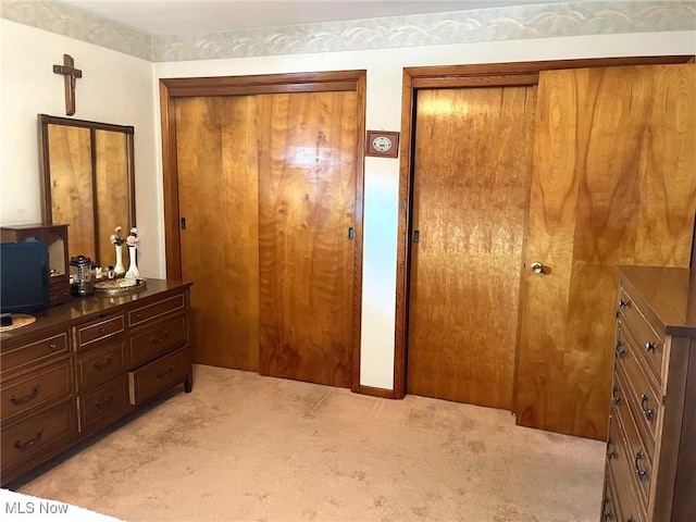 bedroom with light carpet and two closets
