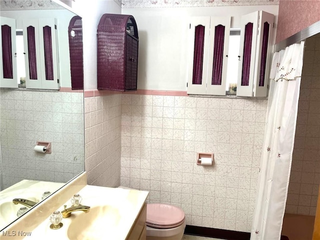 bathroom with toilet, curtained shower, vanity, and tile walls