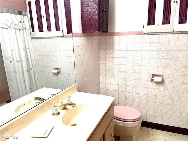 full bath featuring a shower with shower curtain, vanity, tile walls, and toilet