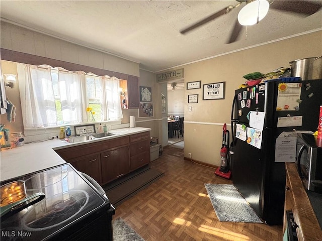 kitchen featuring a textured ceiling, crown molding, a ceiling fan, a sink, and black appliances