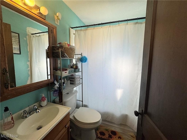 bathroom featuring a shower with curtain, toilet, and vanity
