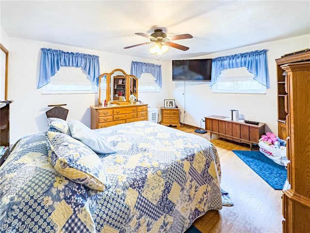 bedroom with a ceiling fan, multiple windows, and wood finished floors