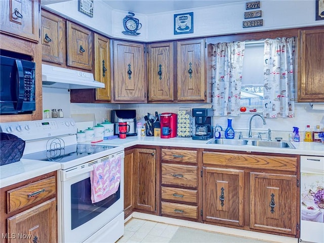 kitchen with light countertops, a sink, brown cabinetry, under cabinet range hood, and white appliances