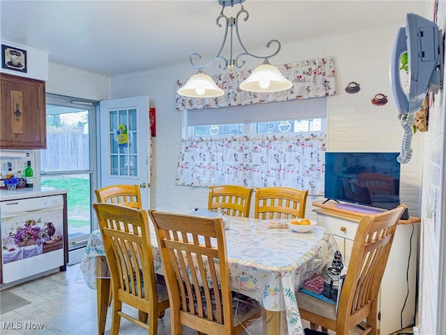 dining area with stone finish floor, crown molding, and brick wall
