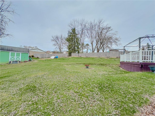 view of yard with an outdoor structure, a fenced backyard, and a shed