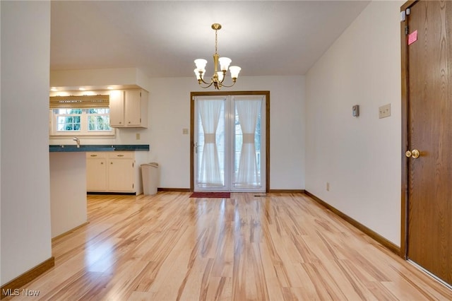 79 Windy Point Dr, Waterford, OH 45786 - kitchen with baseboards, dark countertops, decorative light fixtures, light wood-type flooring, and a notable chandelier