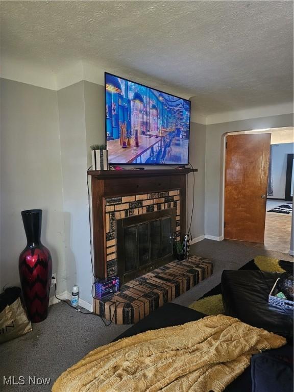 living room with baseboards, a fireplace, carpet flooring, and a textured ceiling