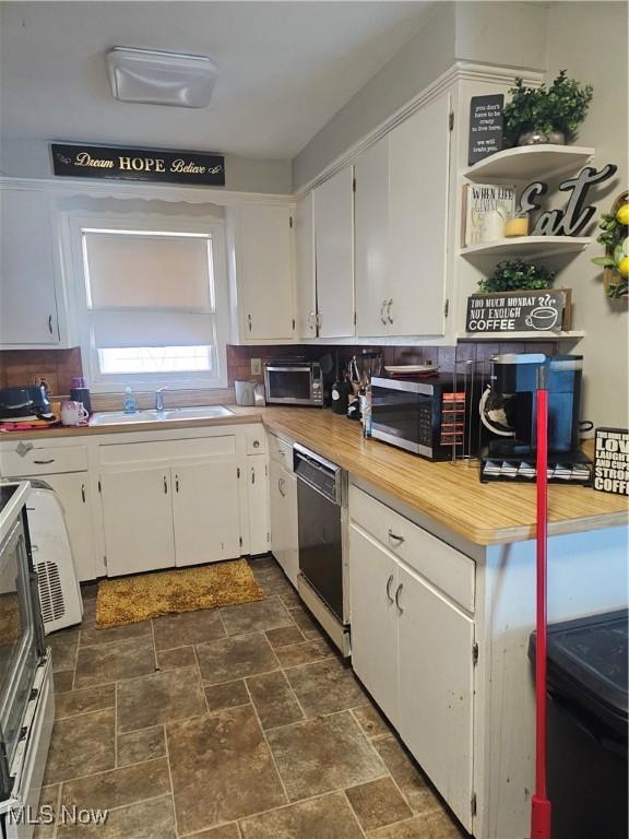 kitchen featuring light countertops, stainless steel microwave, a sink, white cabinets, and dishwashing machine