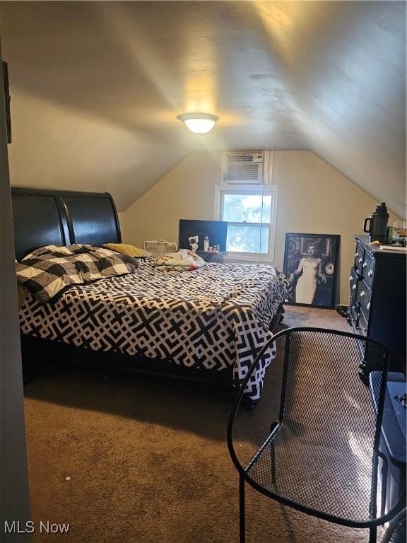 carpeted bedroom featuring a wall mounted AC and vaulted ceiling