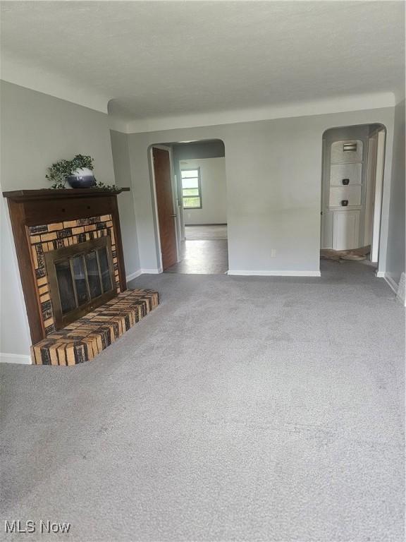 25100 Drakefield Ave, Euclid, OH 44132 - unfurnished living room with arched walkways, carpet floors, and a fireplace