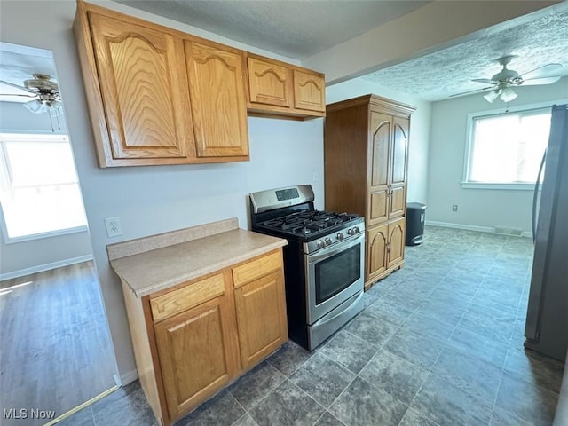 2106 17th St SW, Akron, OH 44314 - kitchen with freestanding refrigerator, stainless steel range with gas stovetop, light countertops, and ceiling fan